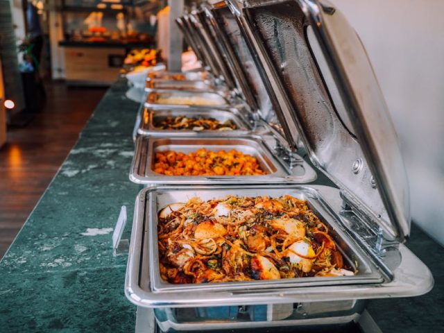 An elegant buffet setup featuring various delicious dishes in stainless steel chafing dishes, perfect for events.