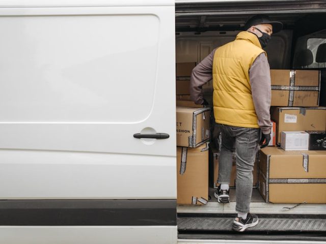 A deliveryman unloading packages from a van, showcasing modern logistics.